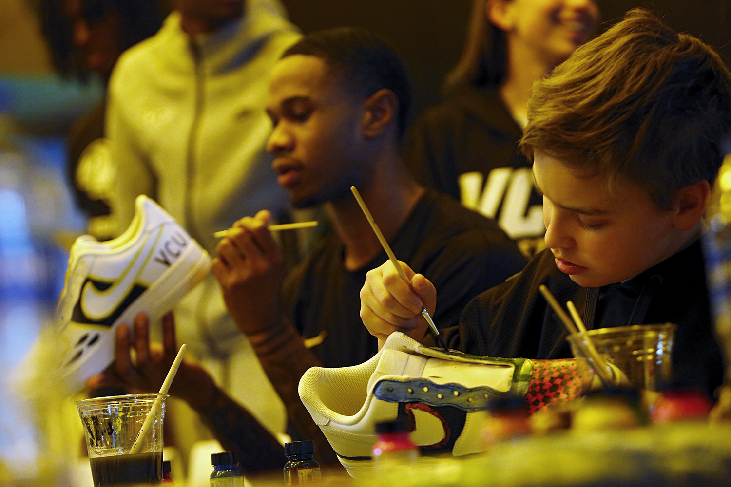 VCU basketball's Zeb Jackson paints sneakers next to CHoR patient Thomas Carley