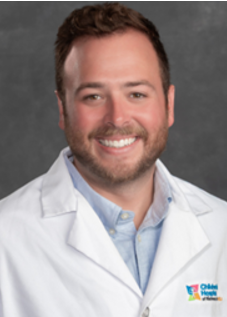 Headshot of Mason Brannon wearing a white physician's coat over a light blue collared shirt.