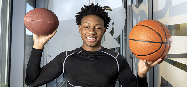 Myles, in athletic wear holding a basketball in each hand.