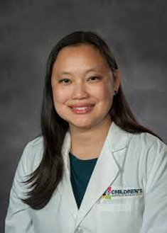 Headshot of Ashlie Tseng wearing a white physician's coat over a forest green shirt.