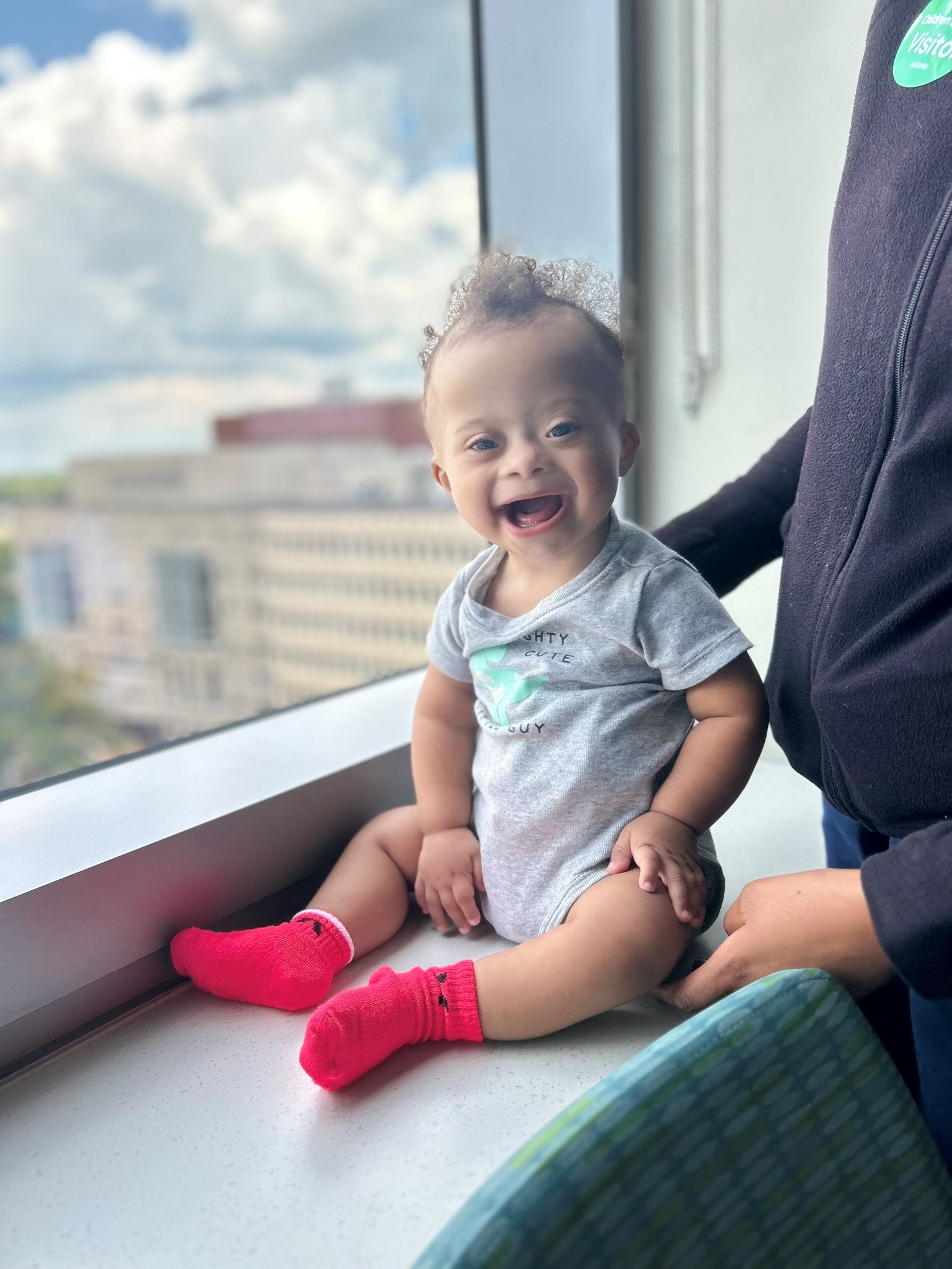 Happy baby sits on next to a window